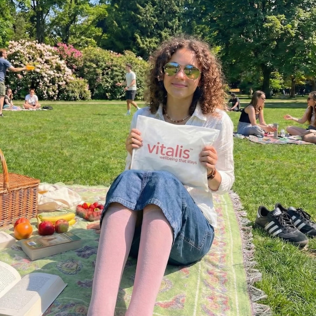 Ragazza al parco con il pacco Vitalis e calze a compressione rosa